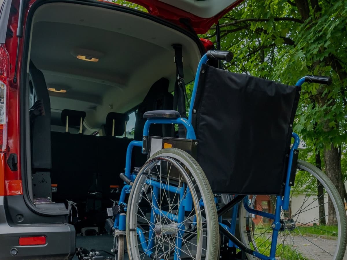 Fauteuil roulant vide devant une fourgonnette adaptée, hayon arrière ouvert